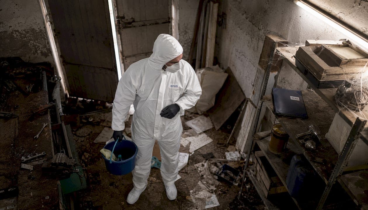 Technicien nettoyant un logement insalubre en tenue de protection