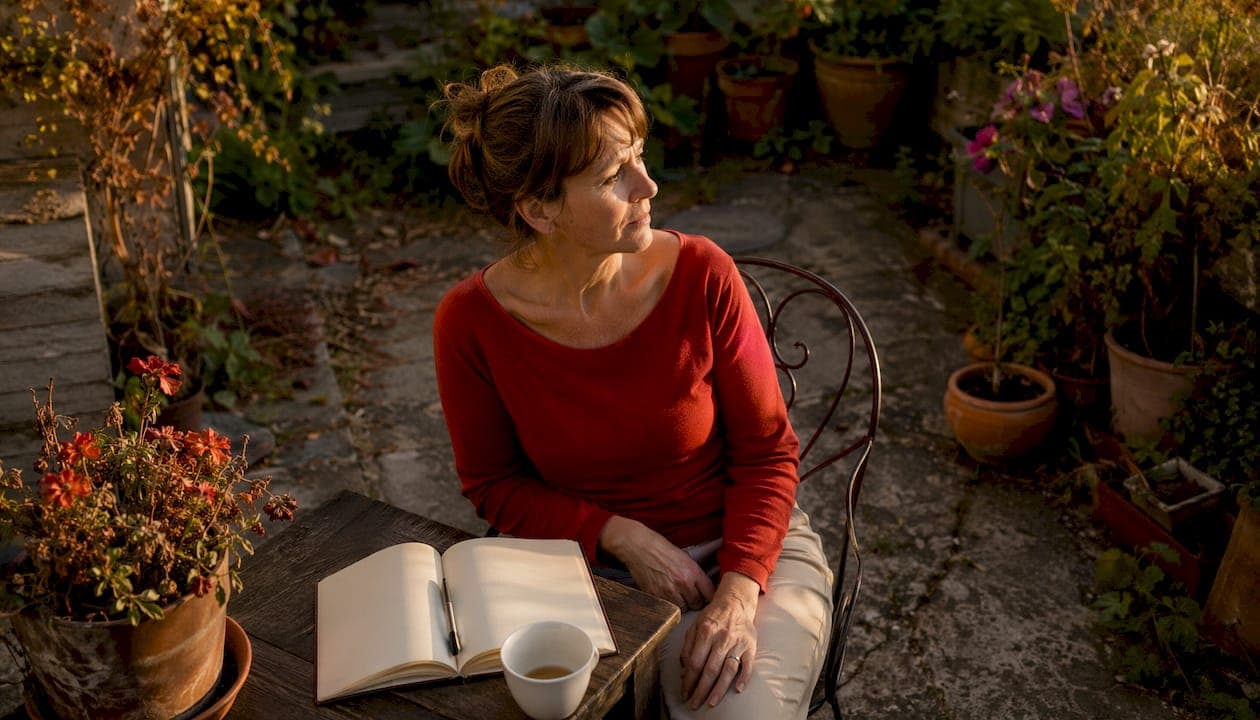 Femme assise dans une cuisine encombrée, en situation d'incurie